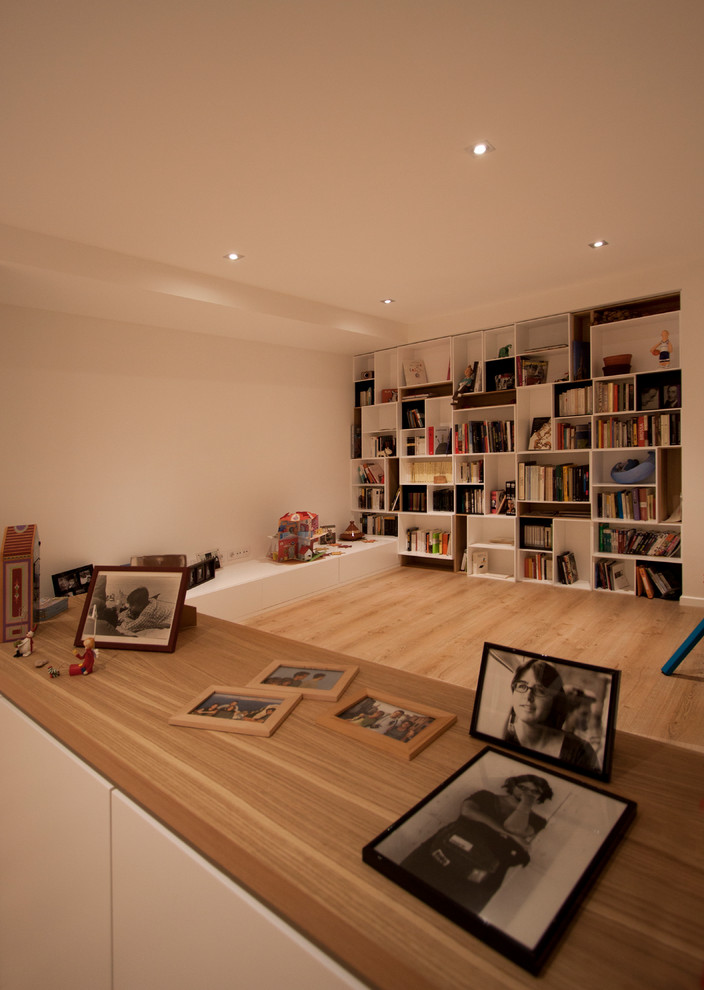 Idée de décoration pour une salle de séjour design de taille moyenne et fermée avec une bibliothèque ou un coin lecture, un mur blanc, un sol en bois brun, aucune cheminée et aucun téléviseur.
