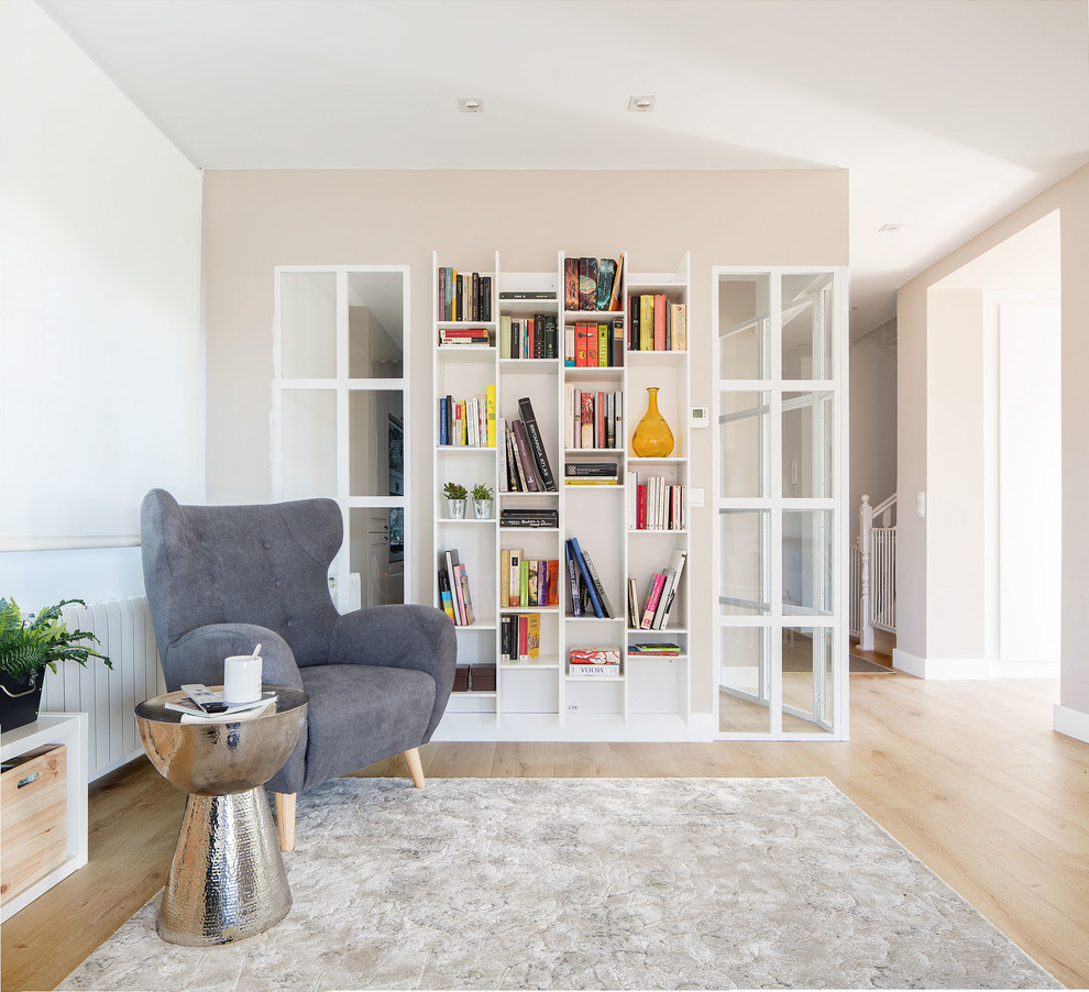 Esempio di un soggiorno minimalista di medie dimensioni e aperto con libreria, pareti bianche, parquet chiaro e pavimento marrone