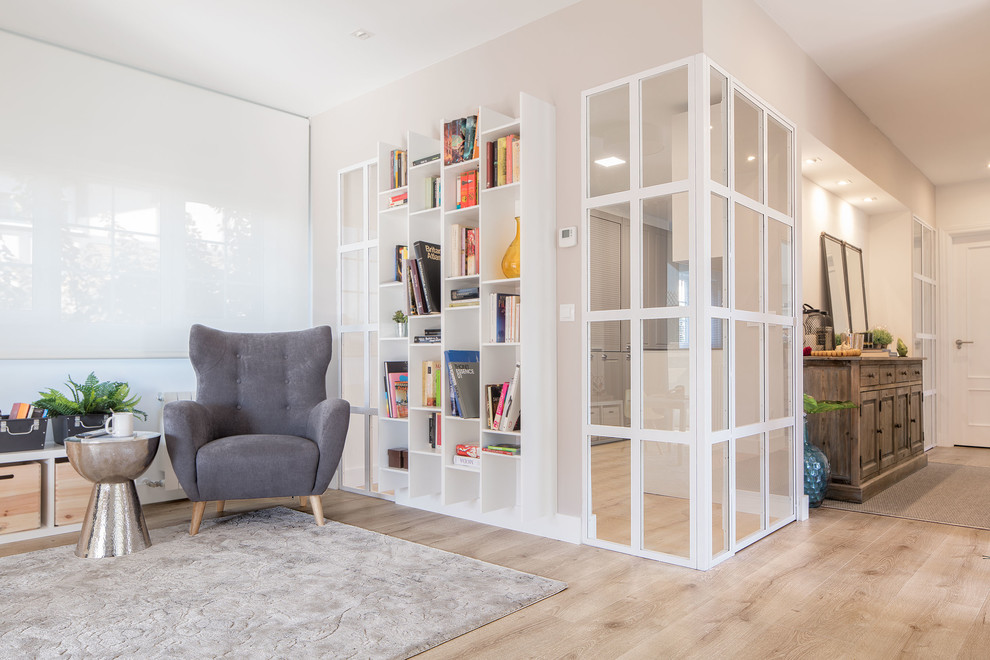 Modelo de sala de estar con biblioteca abierta minimalista de tamaño medio con paredes blancas, suelo de madera clara y suelo marrón