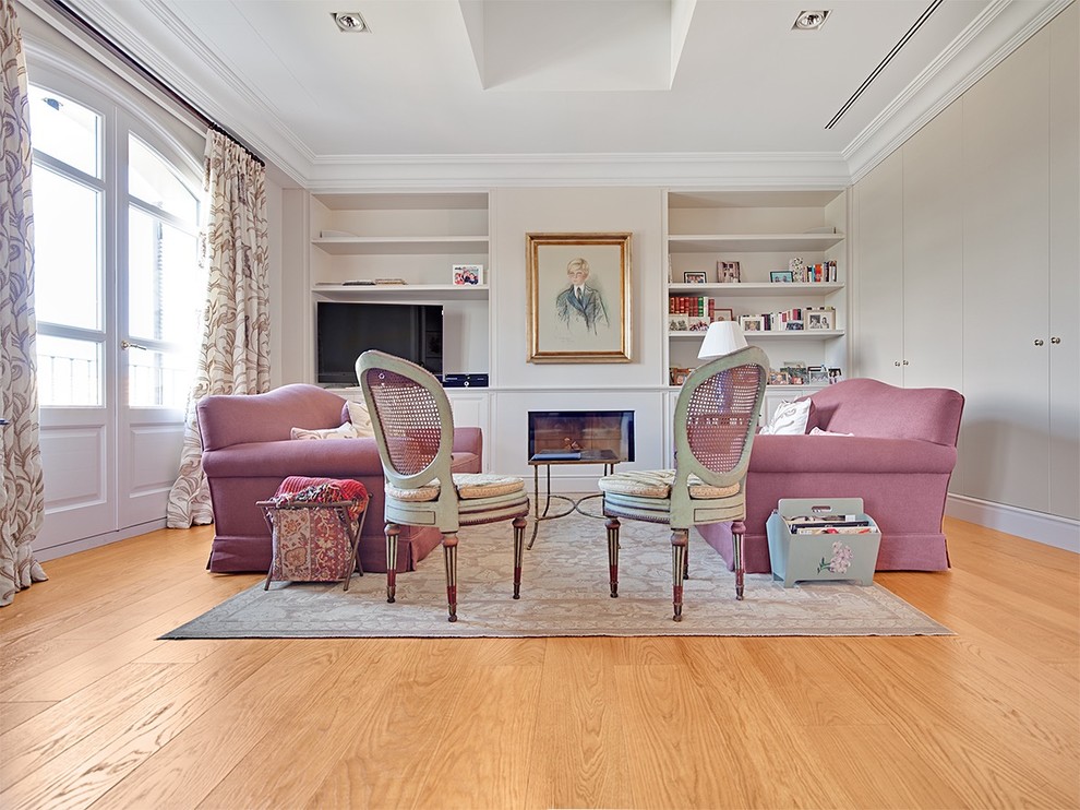 Diseño de sala de estar con biblioteca cerrada tradicional renovada de tamaño medio con paredes beige, suelo de madera en tonos medios, todas las chimeneas y televisor independiente