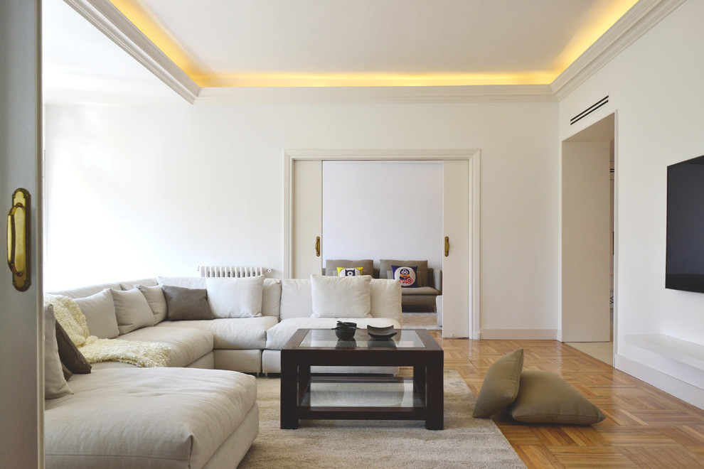 Abgetrenntes, Mittelgroßes Modernes Wohnzimmer ohne Kamin mit weißer Wandfarbe, braunem Holzboden und TV-Wand in Madrid