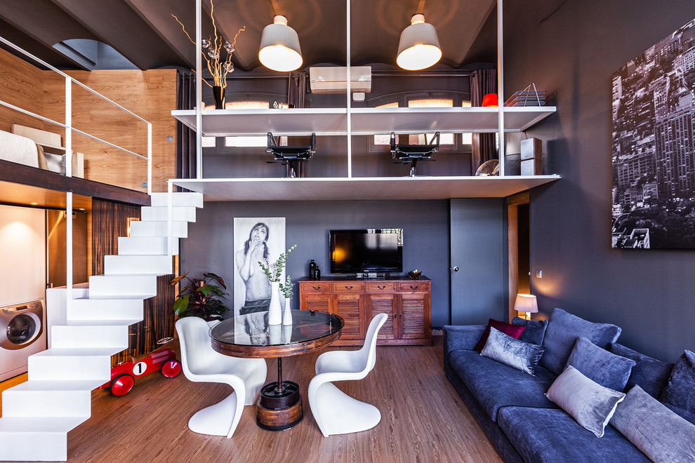 Imagen de sala de estar abierta contemporánea con paredes azules, suelo de madera en tonos medios, televisor independiente y suelo marrón