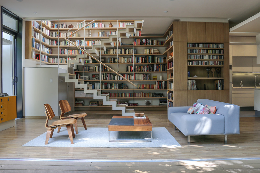 Modelo de sala de estar con biblioteca abierta, actual, sin televisor, con suelo de madera clara y alfombra