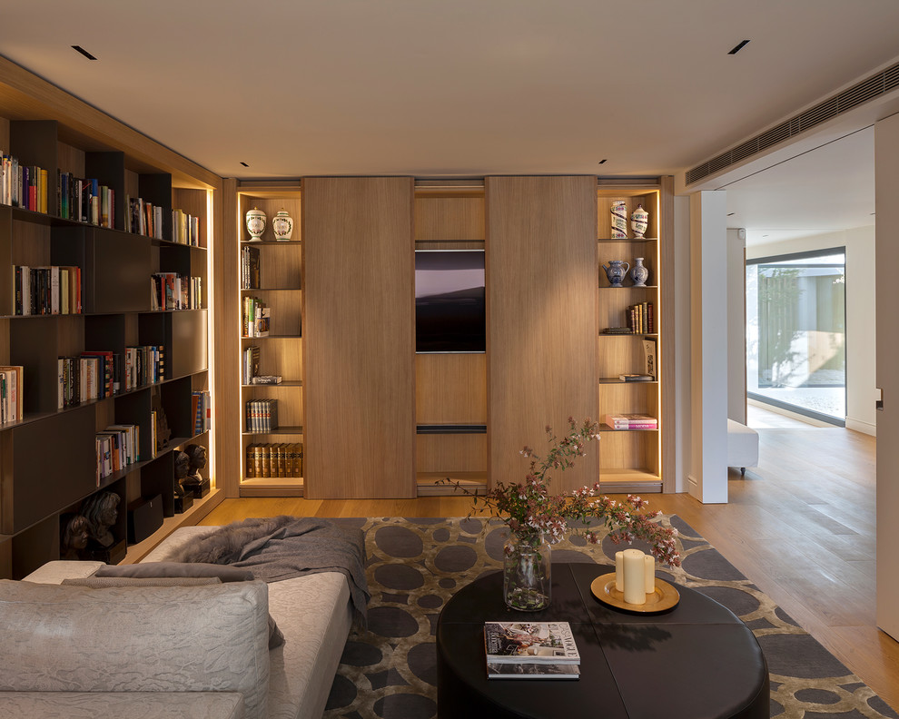 Свежая идея для дизайна: изолированная гостиная комната в современном стиле с с книжными шкафами и полками, белыми стенами, паркетным полом среднего тона, скрытым телевизором и коричневым полом без камина - отличное фото интерьера