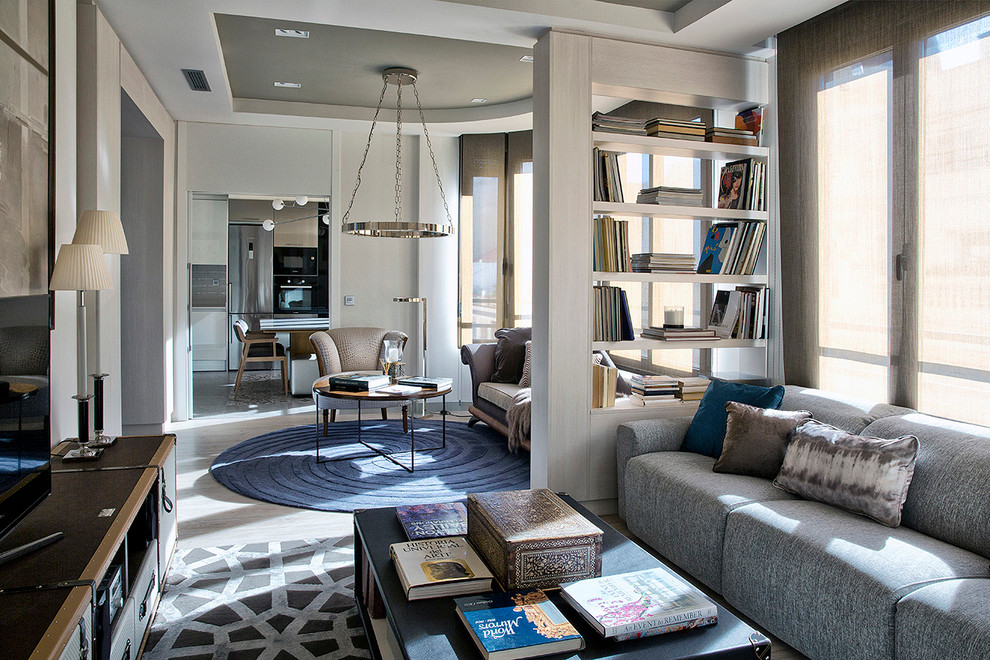 Imagen de sala de estar con biblioteca abierta contemporánea de tamaño medio sin chimenea con paredes beige, suelo de madera clara y pared multimedia