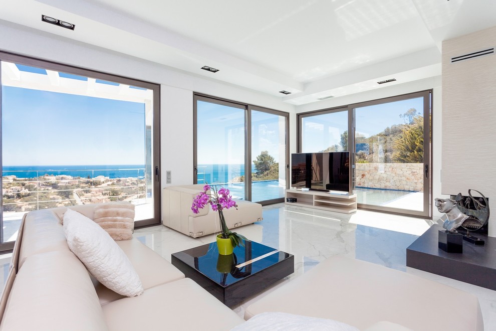 Large contemporary open plan living room in Alicante-Costa Blanca with a freestanding tv, white walls, marble flooring and a corner fireplace.