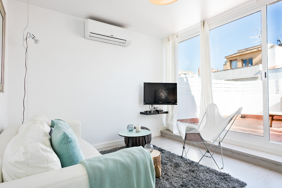 Kleines, Offenes Maritimes Wohnzimmer ohne Kamin mit weißer Wandfarbe, hellem Holzboden und TV-Wand in Barcelona