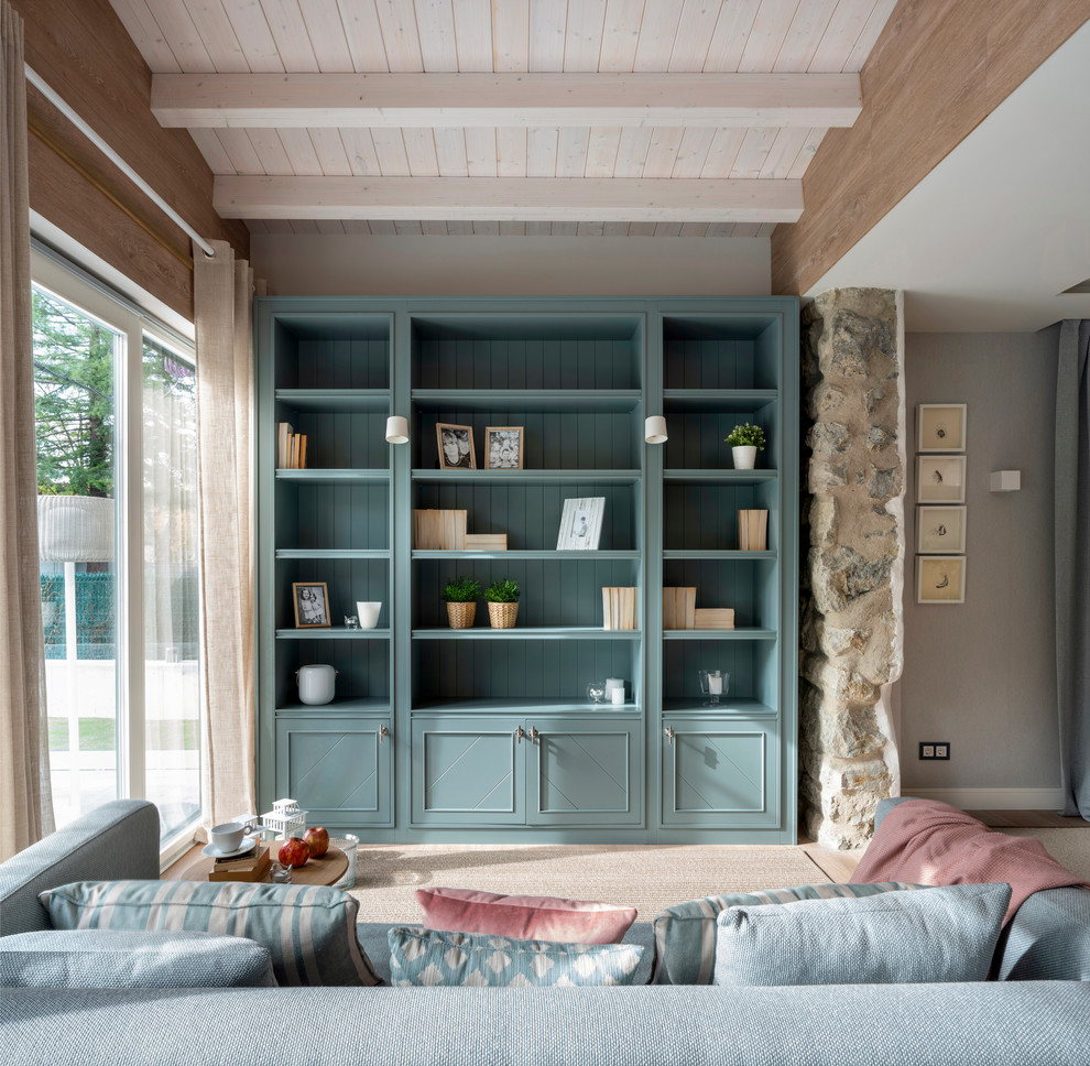 Modelo de sala de estar con biblioteca abierta nórdica grande sin chimenea y televisor con paredes beige, suelo laminado y suelo marrón