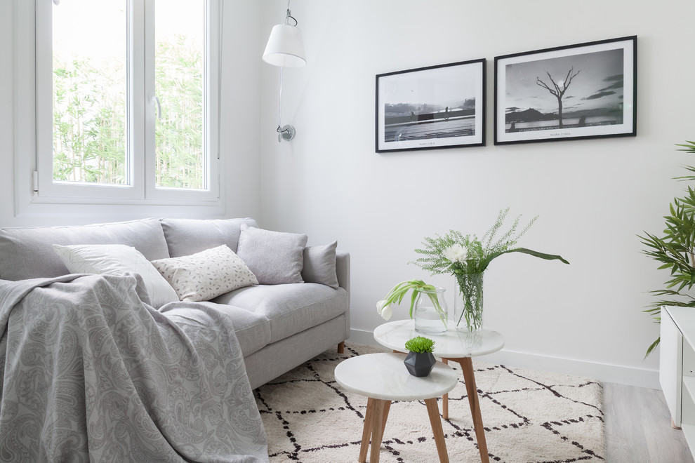 Modelo de sala de estar abierta nórdica pequeña con paredes blancas, suelo laminado, televisor colgado en la pared, suelo gris y alfombra