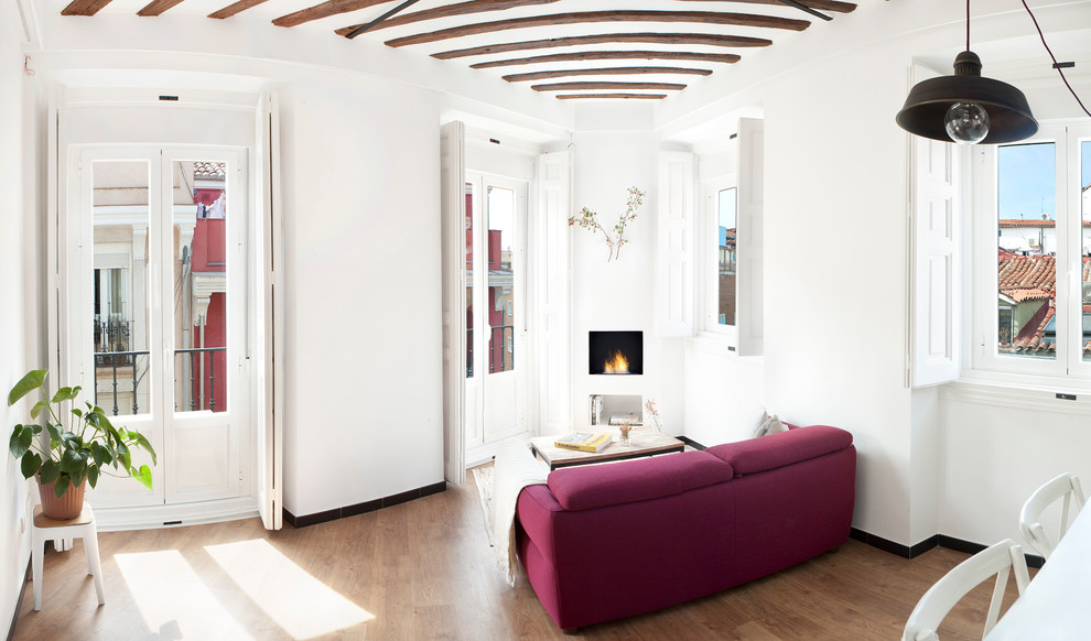 Imagen de sala de estar cerrada actual de tamaño medio sin televisor con paredes blancas, suelo de madera en tonos medios y todas las chimeneas