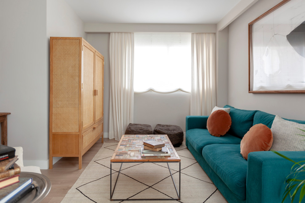 Skandinavisches Wohnzimmer ohne Kamin mit grauer Wandfarbe, hellem Holzboden und verstecktem TV in Sonstige