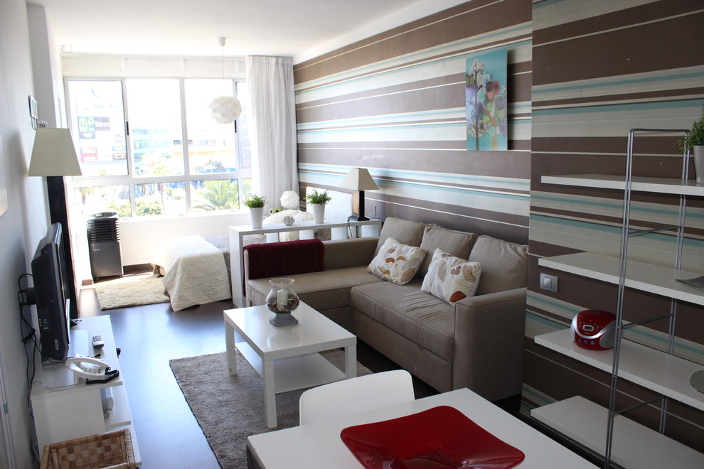 Ejemplo de sala de estar tipo loft moderna pequeña sin chimenea con paredes multicolor y pared multimedia