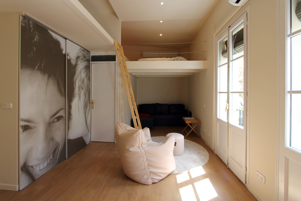 Ejemplo de sala de estar abierta actual pequeña sin chimenea y televisor con paredes beige y suelo de madera en tonos medios