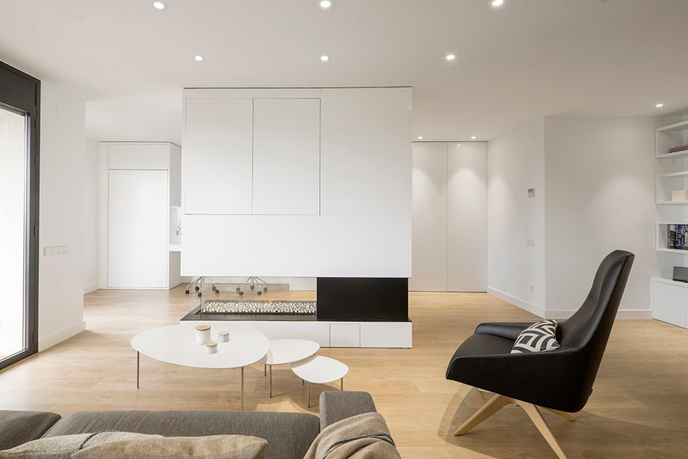 Mittelgroßes, Offenes Nordisches Wohnzimmer mit weißer Wandfarbe, braunem Holzboden, Tunnelkamin, Kaminumrandung aus Holz, Multimediawand und braunem Boden in Barcelona