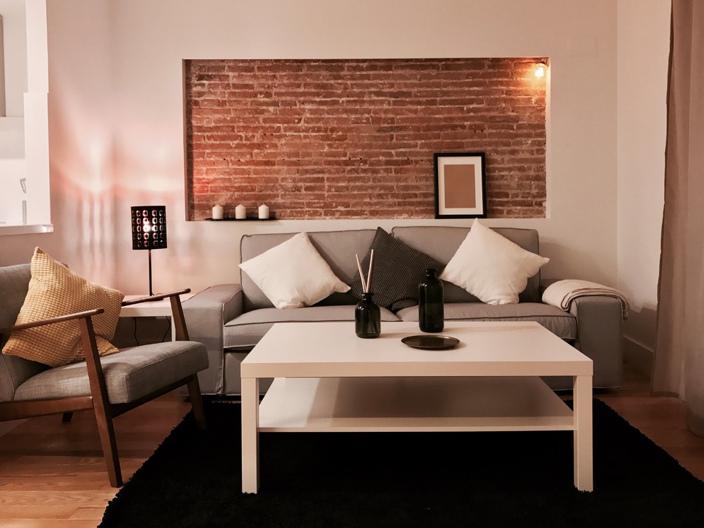 Foto de sala de estar abierta minimalista de tamaño medio con paredes blancas, suelo de madera en tonos medios, televisor independiente y suelo marrón
