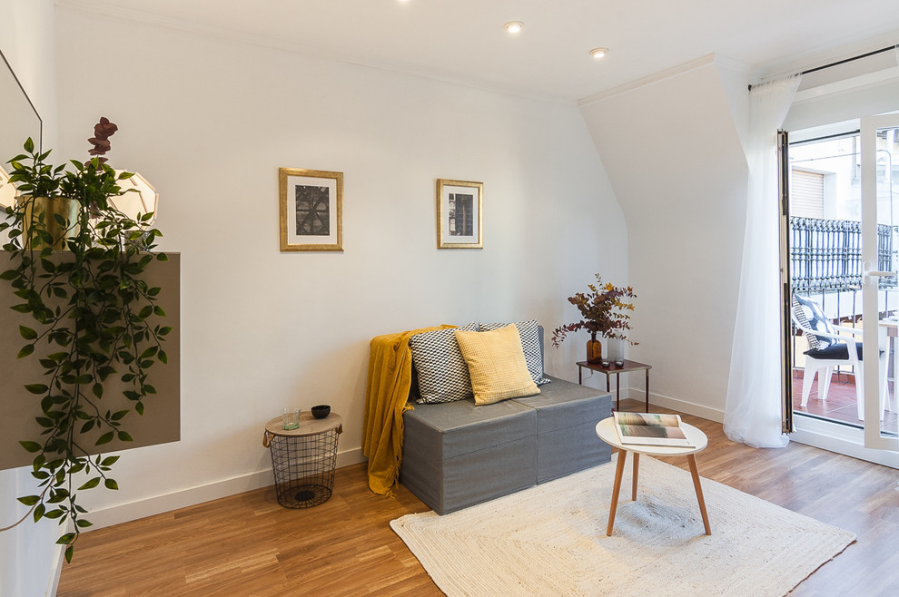 Diseño de sala de estar actual sin chimenea con paredes blancas, suelo laminado y suelo marrón