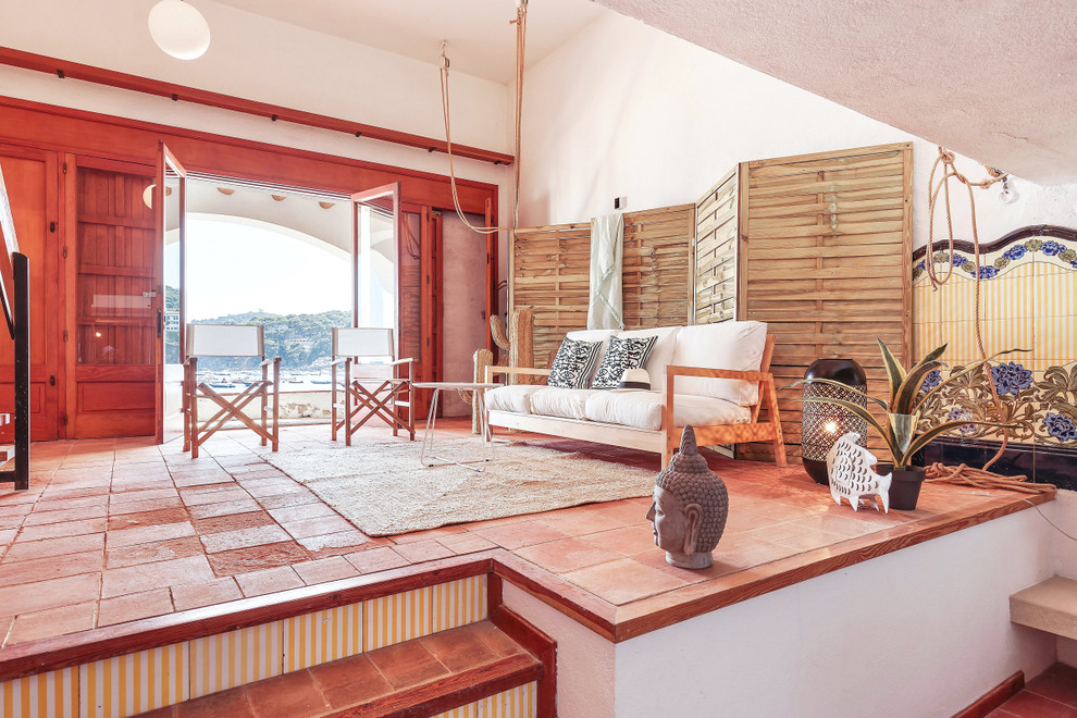Ejemplo de sala de estar abierta mediterránea de tamaño medio sin chimenea con suelo de ladrillo, paredes blancas y suelo rojo