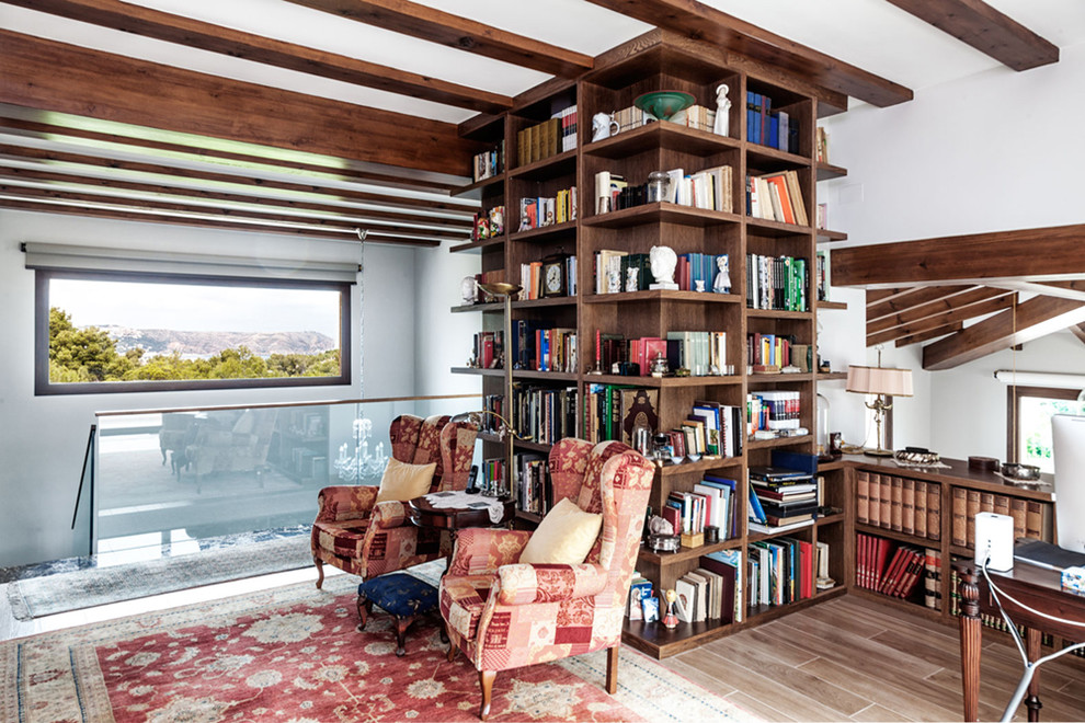Esempio di un soggiorno mediterraneo con libreria, pareti bianche e pavimento in legno massello medio