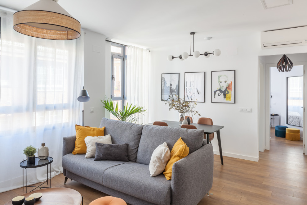 Immagine di un soggiorno contemporaneo di medie dimensioni e aperto con pareti bianche, pavimento in legno massello medio, TV autoportante e pavimento marrone