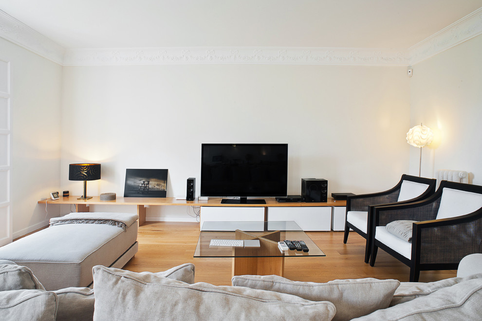 Imagen de sala de estar moderna de tamaño medio sin chimenea con paredes blancas, suelo de madera en tonos medios y pared multimedia