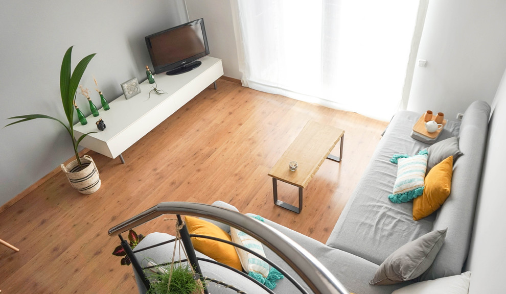 Kleines, Offenes Nordisches Wohnzimmer mit weißer Wandfarbe, Laminat, Eck-TV und braunem Boden in Barcelona