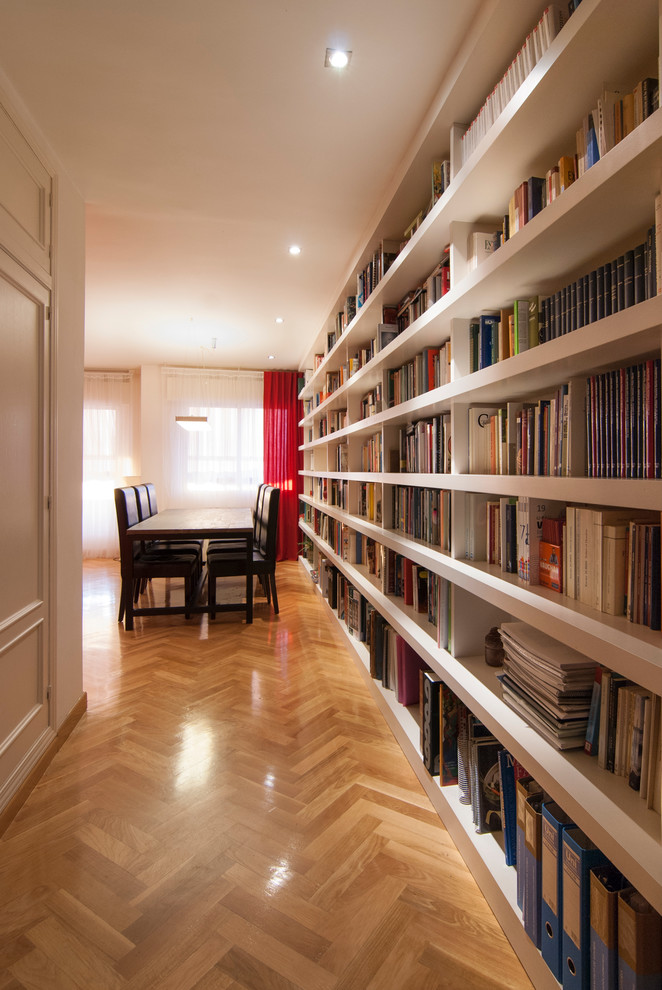 Foto de sala de estar con biblioteca abierta clásica renovada grande sin chimenea y televisor con paredes blancas y suelo de madera en tonos medios