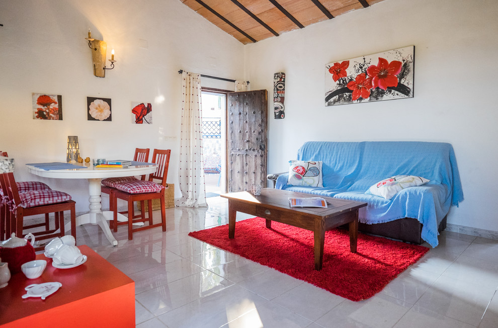 На фото: изолированная гостиная комната среднего размера в средиземноморском стиле с белыми стенами, полом из керамической плитки и синим диваном без камина, телевизора с