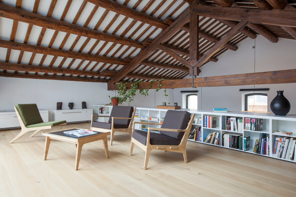 Exempel på ett stort lantligt allrum på loftet, med ett bibliotek, vita väggar och ljust trägolv