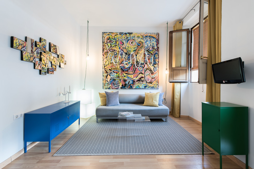 Ejemplo de sala de estar cerrada contemporánea de tamaño medio sin chimenea con paredes blancas, suelo de madera clara, televisor colgado en la pared y suelo beige