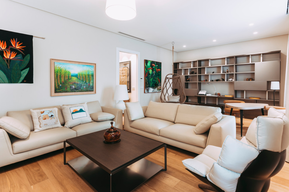 Réalisation d'une salle de séjour design avec un mur blanc, un sol en bois brun et un sol marron.