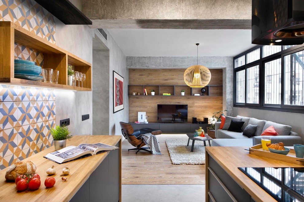 Diseño de sala de estar abierta industrial de tamaño medio sin chimenea con suelo de cemento, suelo gris, televisor independiente y alfombra