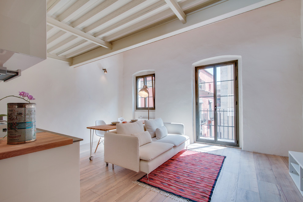 Imagen de sala de estar abierta mediterránea de tamaño medio sin chimenea con paredes blancas y suelo de madera en tonos medios