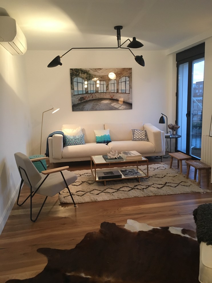 Imagen de sala de estar cerrada escandinava pequeña sin chimenea con paredes blancas y suelo de madera en tonos medios