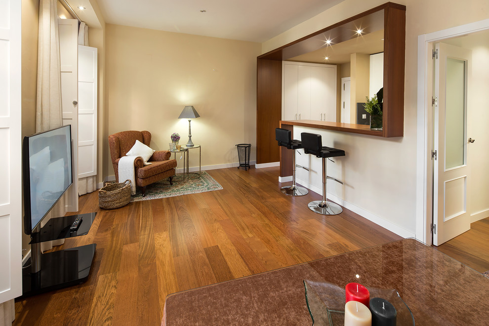 Modelo de sala de estar abierta minimalista de tamaño medio con paredes beige, suelo de madera en tonos medios y televisor independiente