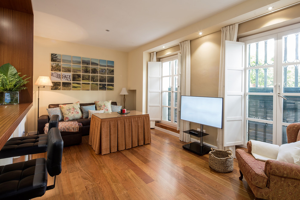 Diseño de sala de estar abierta moderna de tamaño medio con paredes beige, suelo de madera en tonos medios y televisor independiente