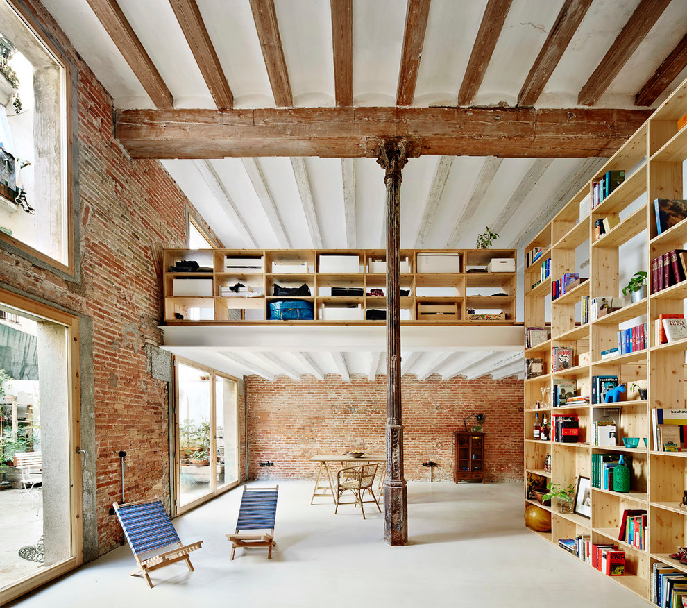 Large urban concrete floor family room library photo in Barcelona with orange walls, no fireplace and no tv