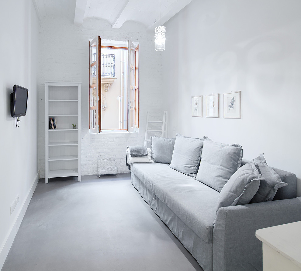 Esempio di un soggiorno mediterraneo con TV a parete, pareti bianche, pavimento in cemento e pavimento grigio