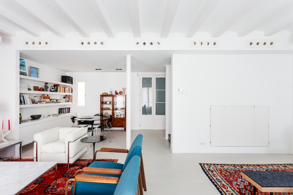 Immagine di un soggiorno minimal di medie dimensioni e aperto con libreria, pareti bianche, pavimento in cemento e pavimento grigio