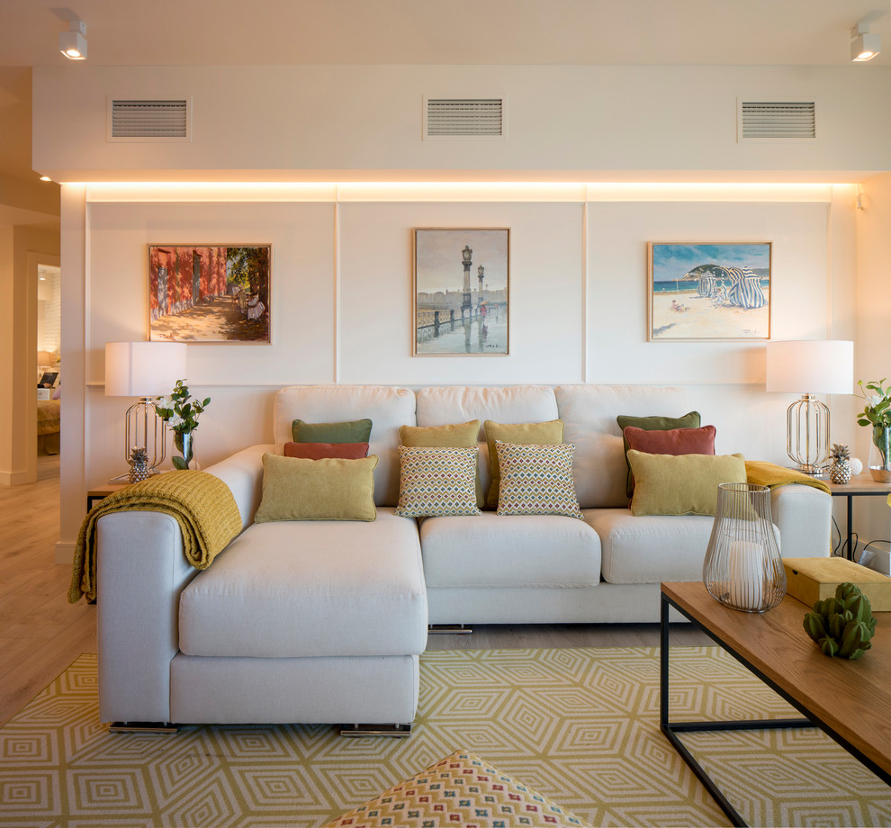 Immagine di un soggiorno classico aperto con libreria, pareti beige, pavimento in laminato, nessun camino, parete attrezzata e pavimento beige