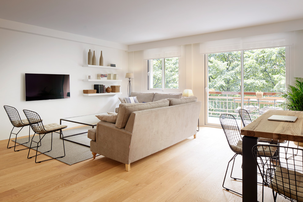Diseño de sala de estar abierta urbana grande sin chimenea con paredes blancas, suelo de madera en tonos medios, televisor colgado en la pared y suelo marrón