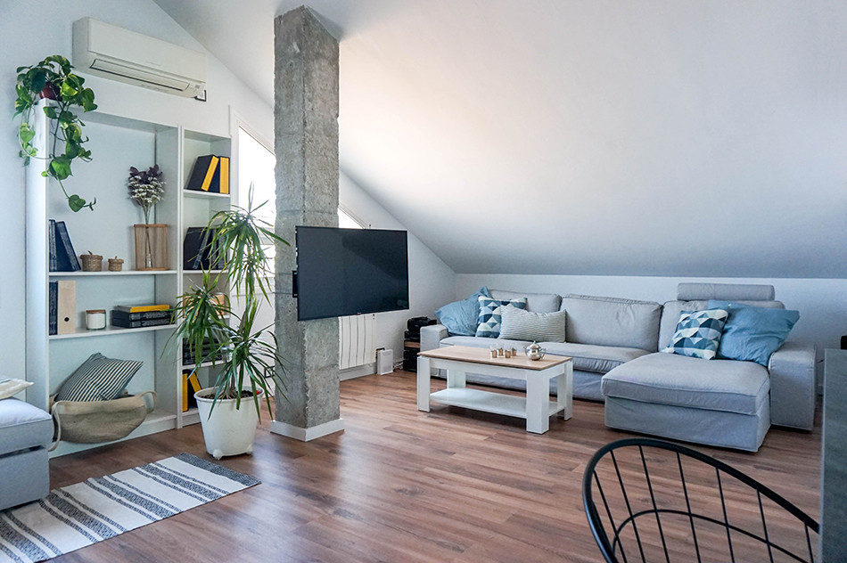 Diseño de sala de estar tipo loft urbana de tamaño medio sin chimenea con paredes blancas, suelo laminado, televisor en una esquina y suelo marrón