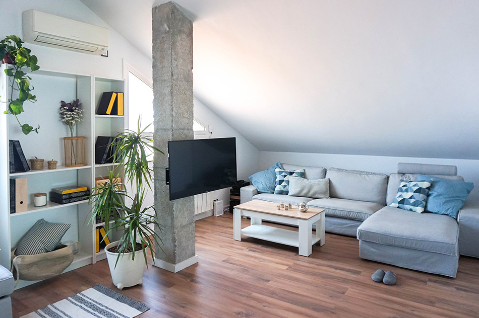 Foto de sala de estar tipo loft urbana de tamaño medio sin chimenea con paredes blancas, suelo laminado, televisor en una esquina y suelo marrón