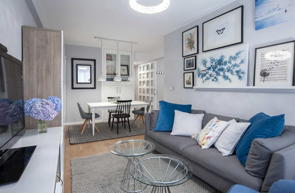 Diseño de sala de estar abierta nórdica pequeña sin chimenea con paredes grises, suelo de madera en tonos medios, televisor independiente y alfombra