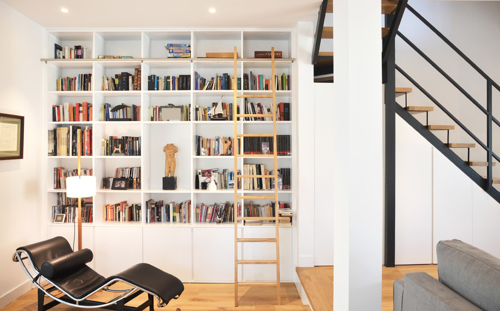 Modernes Wohnzimmer mit weißer Wandfarbe, braunem Holzboden und braunem Boden in Madrid