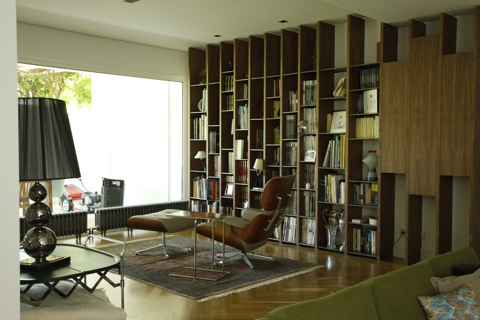 Modelo de sala de estar con biblioteca abierta clásica renovada de tamaño medio sin chimenea y televisor con paredes blancas y suelo de madera en tonos medios