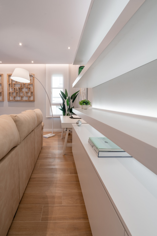 Esempio di un grande soggiorno minimal chiuso con libreria, pareti beige, pavimento con piastrelle in ceramica, TV a parete e pavimento marrone