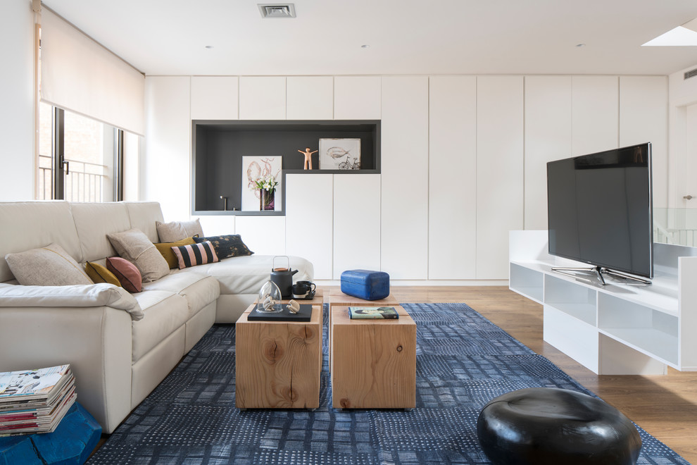 Imagen de sala de estar con barra de bar tipo loft contemporánea grande con paredes blancas, suelo de madera en tonos medios, televisor independiente y suelo marrón