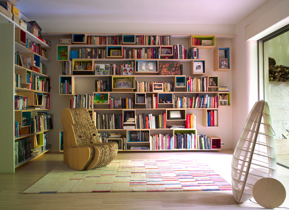 Cette photo montre une salle de séjour chic de taille moyenne et fermée avec une bibliothèque ou un coin lecture, un mur blanc, parquet clair, aucune cheminée et aucun téléviseur.