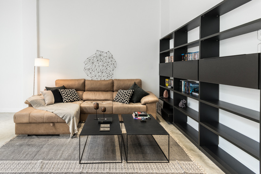Modelo de sala de estar con biblioteca de tamaño medio con paredes blancas y suelo de cemento