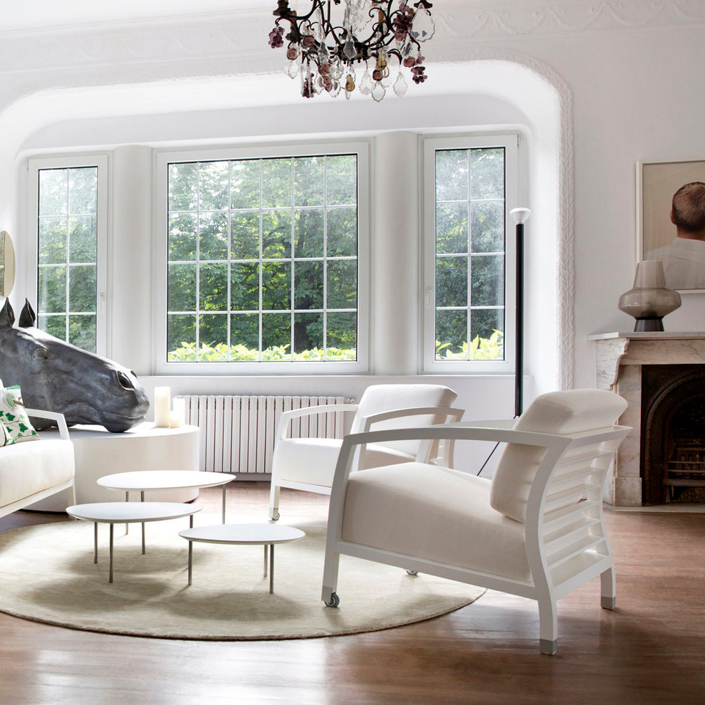 Mittelgroßes, Offenes Modernes Wohnzimmer mit weißer Wandfarbe, braunem Holzboden und Kamin in Sonstige